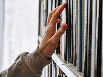 Hand skimming books on shelf